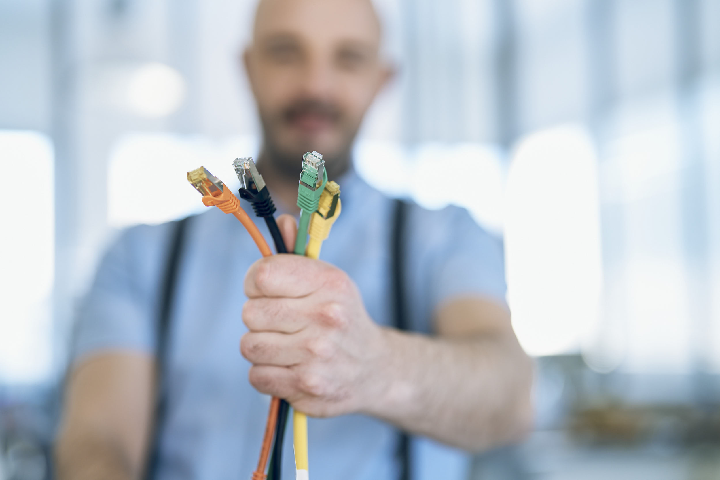 Fachperson hält mehrere Netzwerkkabel in die Kamera